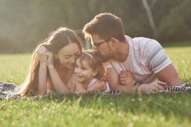 Anne ve baba birlikte mutlu zaman geçiriyorlar. Küçük kız gün batımında ailesiyle dışarıda oynuyor..