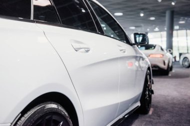 Manzarayı kapat. Modern beyaz renkli güzel arabanın sağ tarafındaki fotoğraf kapalı bir yere park edilmiş..