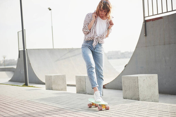 A young sports woman who rides in a park on a skateboard