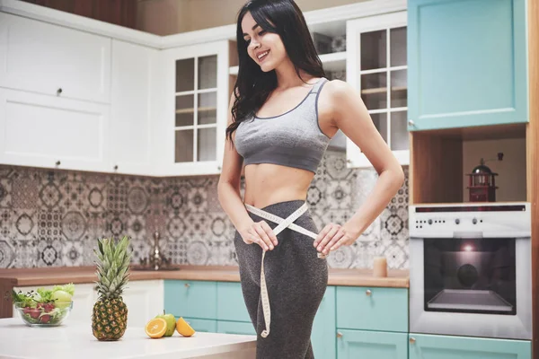 Retrato Uma Mulher Medindo Seu Corpo Magro Fundo Cozinha Fitness — Fotografia de Stock