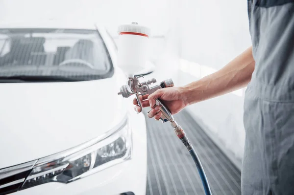 gun with paint in the hands of a man to paint a car.