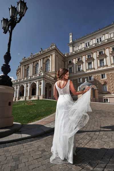 Beautiful, elegant bride with a perfect wedding dress, poses around beautiful architecture.