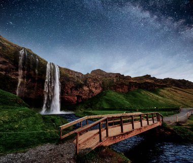 Seljalandfoss şelalesi geceleyin. Nehrin üzerindeki köprü. Şahane bir doğa. İzlanda. Derin gökyüzü gökyüzü fotoğrafı