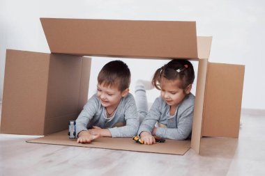İki küçük çocuk ve kız yeni bir eve taşındılar. Kavramsal fotoğraf. Çocuklar eğlenir ve küçük arabalar oynar.