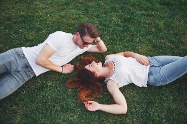 Parktaki çimlerin üzerinde yatan romantik bir çift genç. Üst görünüm.