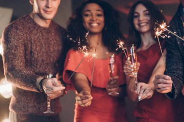 Neşeli bir atmosfer. Çok ırklı arkadaşlar yeni yılı kutluyor. Bengal ışıkları ve bardaklarla içki içiyorlar..