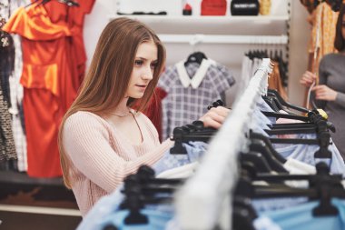 Satılık, moda, tüketim ve insanlar kavramı - alışveriş merkezi veya giyim mağazası giysiler seçmek torbaları ile mutlu genç kadın.
