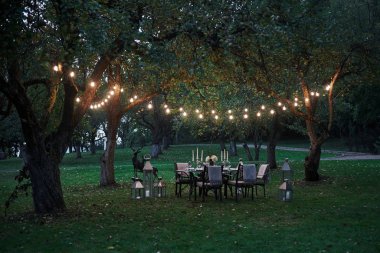 Ampuller büyüleyici bir atmosfer yaratır. Yemek ve ziyaretçiler için hazırlanmış masa. Akşam vakti..