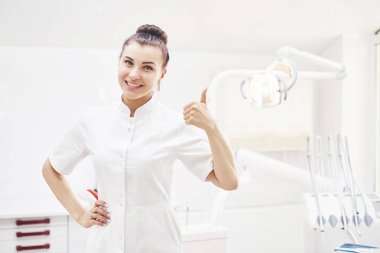 Tıbbi geçmişinde aletleri olan mutlu genç bir dişçi. Stomatoloji ve sağlık konsepti.