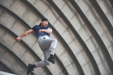 Genç adam şehrin kentsel alanında parkur atlayışı yapıyor güneşli bahar günü