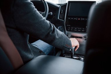 İş kavramı. Modern araba sürerken yetişkin pesonunun vites koluna dokunuşunu yakından izlemek.