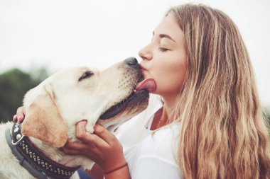 Parkta yeşil çimlerin üzerinde güzel bir köpeği olan güzel bir kızı çerçevelet.