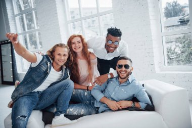 Harika vakit geçiriyorum. Arka planda pencereleri olan güzel insanlar kanepede oturuyor..