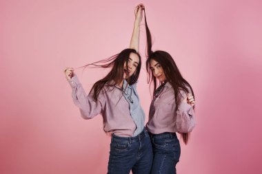 Sadece Ramdom 'un eğlenceli hareketleri. Stüdyoda pembe arka planda eğlenen genç kadınlar. Sevimli ikizler.