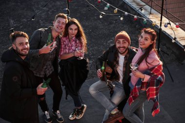 Kameraya bakıyorum. İçki içen, gitar çalan ve dekoratif renkli ampullerle çatıda eğlenen genç bir arkadaşın en iyi görüntüsü..