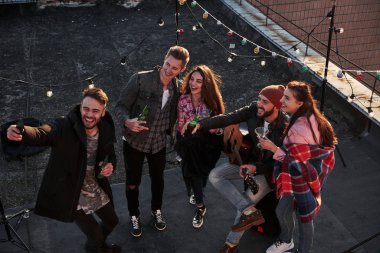 Samimi duygular. Dekoratif renkli ampullerle çatıda eğlenirken selfie çeken genç bir arkadaşın en iyi görüntüsü..