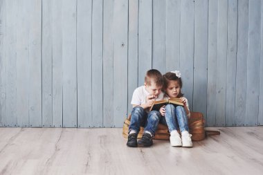 Büyük seyahate hazırız. Küçük mutlu kız ve çocuk ilginç bir kitap okuyor büyük bir evrak çantası taşıyor ve gülümsüyor. Seyahat, özgürlük ve hayal gücü kavramı.