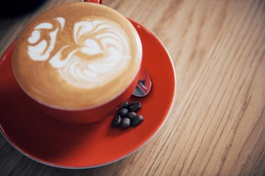 Bir fincan kahve kapuçino, ahşap masanın üstünde latte sanat eseri, eski kahve rengi.