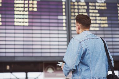 Omzunda çantasıyla havaalanına koşan yakışıklı bir genç..