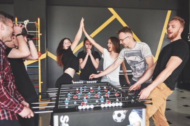 Gülümseyen gençler tatildeyken masa futbolu oynuyorlar.