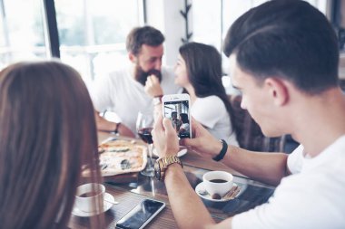 Meyhanede bir grup gülümseyen insanın dinlendiği masada lezzetli bir pizza..