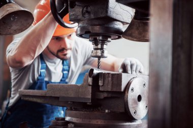 Başlık takmış deneyimli bir operatör. Metal endüstrisi konsepti profesyonel mühendis metal işçisi imalat atölyesinde Cnc değirmen makine merkezi işletiyor.