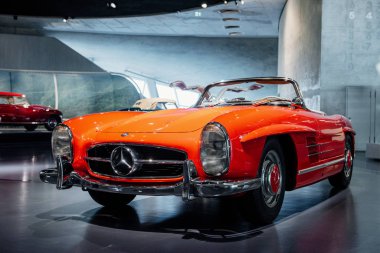 Stuttgart, Almanya - 16 Ekim 2018: Mercedes Müzesi. Kırmızı ve beyaz araç arkada. Güzel turuncu renkli retro araba ön taraftan yakalandı..