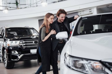 Gururlu sahipler. Güzel, genç, mutlu bir çift yeni satın aldıkları arabalarının yanında durup gülümsüyorlar. Kameranın anahtarlarını neşeyle gösteriyorlar. Fotokopi makinesinin anahtarlarını gösteriyorlar..