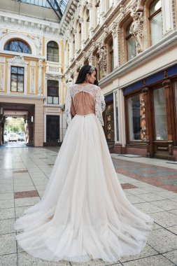 Mükemmel gelinliği olan güzel, zarif gelin, güzel bir mimarinin etrafında poz veriyor.