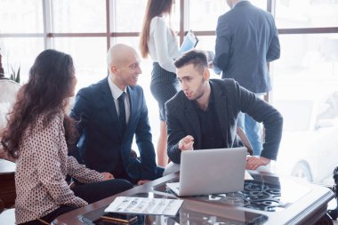 Genç iş arkadaşları modern ofiste büyük iş görüşmeleri yapıyorlar. Takım çalışması insanları konsepti.