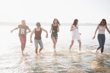 Mutlu arkadaşlar kumsalda eğlenir - Gençler yaz tatillerinde açık havada oynarlar.