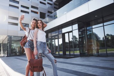 Üniversitenin kampüsünün yakınında sırt çantalı iki güzel mutlu öğrenci kız. Eğitim ve eğlence kavramı.