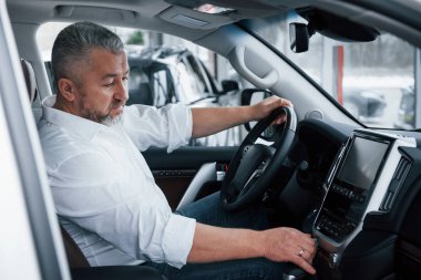 Yeni bir otomobil alıp test ediyorum. Resmi kıyafetli kıdemli işadamı lüks bir arabada oturur ve müzik çaların düğmelerine basar..