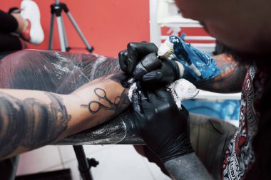 Dövme makinesini kapat. Siyah steril eldivenler ustası. Kuaförde resim yapıyor..