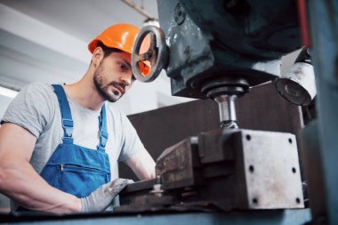 Büyük bir atık geri dönüşüm fabrikasında kasketli genç bir işçinin portresi. Mühendis, makinelerin ve diğer ekipmanların çalışmalarını izler..