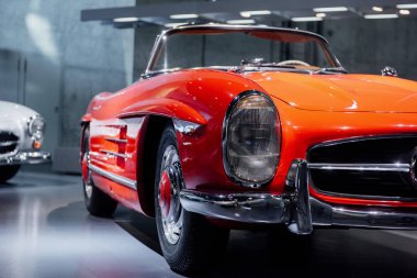 Stuttgart, Almanya - 16 Ekim 2018: Mercedes Müzesi. Arka planda beyaz bir otomobil daha. Güzel turuncu renkli retro araba ön taraftan yakalandı..