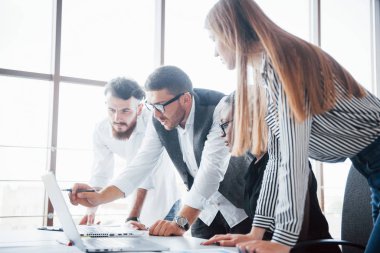 Ofiste dizüstü bilgisayarla oturan ve bir meslektaşını dinleyen şık bir bayan.