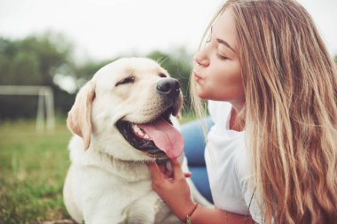 Parkta yeşil çimlerin üzerinde güzel bir köpeği olan güzel bir kızı çerçevelet.