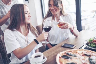 En iyi arkadaşlardan oluşan bir grup pizza ve bir bardak içkiyle kafe içinde kutlama yapıyorlar..