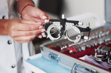 Changing the lenses. Female hands holding the optical device for eye testing. clipart