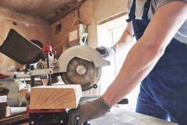 İş elbisesi içinde bıçkıhane değirmeninde öğütücü kullanıyor.