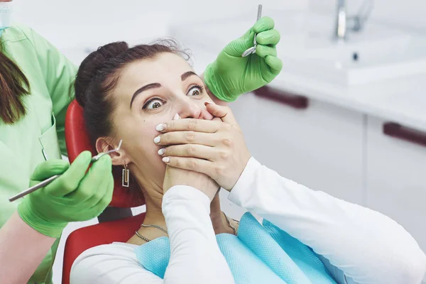 Frightened girl at dentist office covered mouth with hands. Concept phobia dental office.