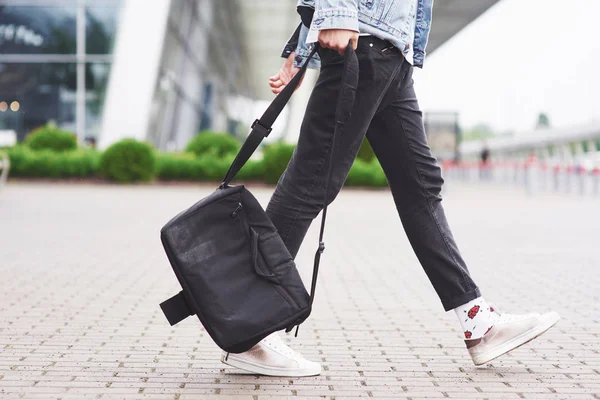 Young handsome man with a bag on his shoulder in a hurry to the airport.