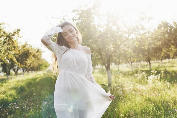 Młoda Dziewczyna Białej Długiej Sukience Spaceruje Ogrodzie Piękny Zachód Słońca — Zdjęcie stockowe