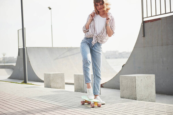 A young sports woman who rides in a park on a skateboard