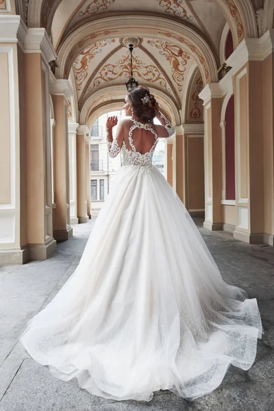 Beautiful, elegant bride with a perfect wedding dress, poses around beautiful architecture.
