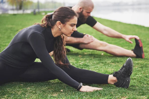 Fitnesspaar Dat Zich Buiten Het Park Bij Het Water Uitstrekt — Stockfoto