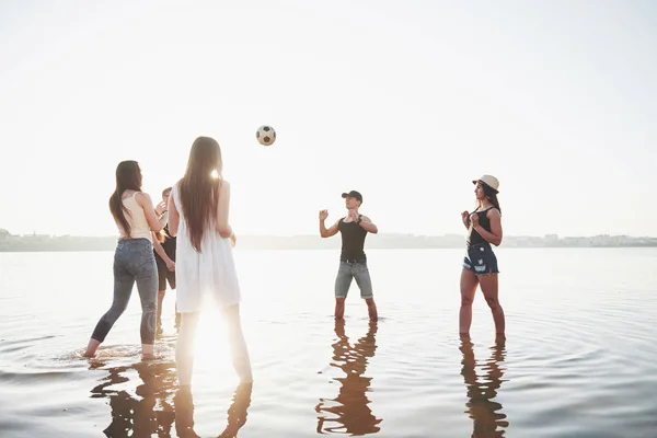 笑着的年轻朋友在湖畔打沙滩排球 — 图库照片