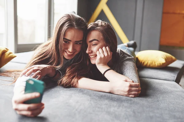 Dwie Słodkie Uśmiechnięte Bliźniaczki Trzymające Smartfona Robiące Selfie Dziewczyny Leżą — Zdjęcie stockowe