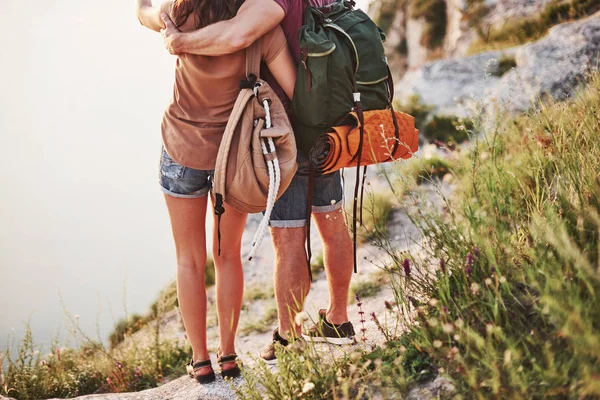 移動には装備が必要だ若いカップルは 湖を背景に豪華な岩の端に積極的に休暇を過ごすことにしました — ストック写真